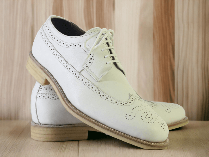 Expertly crafted from genuine leather, these handmade white Oxfords boast impeccable quality and timeless style. The intricate brogue and wing tip details add a touch of sophistication to any dress shoe collection. Elevate your professional look with these luxurious and durable shoes.