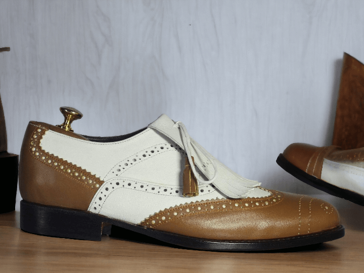 Expertly crafted by hand, these White Tan Wing Tip Brogue Shoes feature luxurious leather with eye-catching fringes. With a designer touch, these shoes exude sophistication and style, adding a touch of elegance to any outfit. Trust in the quality and expertise of these handmade shoes to elevate your wardrobe