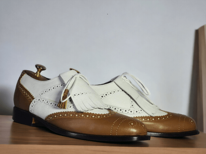 Expertly crafted by hand, these White Tan Wing Tip Brogue Shoes feature luxurious leather with eye-catching fringes. With a designer touch, these shoes exude sophistication and style, adding a touch of elegance to any outfit. Trust in the quality and expertise of these handmade shoes to elevate your wardrobe