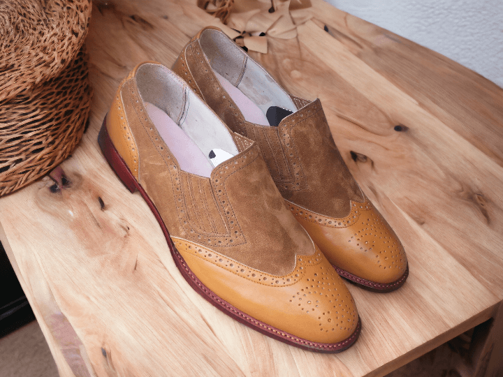 Expertly crafted by hand, these men's brown leather and suede loafers exude both style and comfort. The classic wing tip brogue design adds a touch of sophistication to any outfit, making them the perfect choice for the fashion-forward man. Stand out in these statement shoes that are both fashionable and functional.