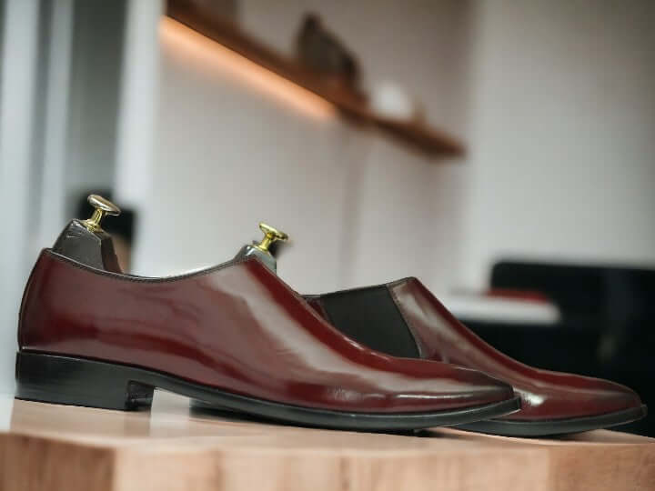 These Men's Maroon Patent Chelsea Shoes are handcrafted from high-quality leather, providing a polished and sophisticated look suitable for any dressy occasion. Featuring the classic Chelsea style with a sleek patent finish, these shoes are sure to elevate any outfit. Perfect for any fashion-forward man looking to make a statement.