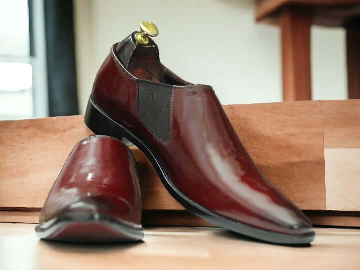 These Men's Maroon Patent Chelsea Shoes are handcrafted from high-quality leather, providing a polished and sophisticated look suitable for any dressy occasion. Featuring the classic Chelsea style with a sleek patent finish, these shoes are sure to elevate any outfit. Perfect for any fashion-forward man looking to make a statement.