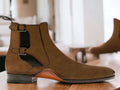 Introducing our Bespoke Buckle Chelsea Boots, featuring handmade suede and a stylish buckle design. These dress formal slip on boots are perfect for any occasion, providing both style and comfort. Step up your footwear game with our ankle-high boots for men.